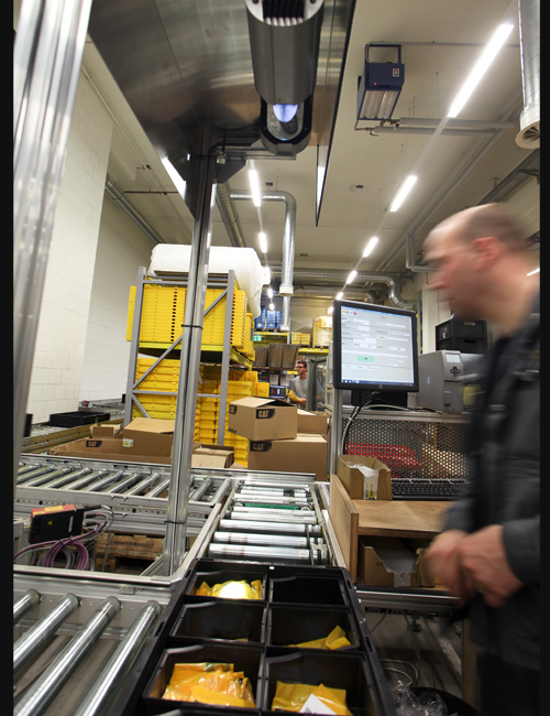 Mitarbeiter kommissioniert mit der Behälterausleuchtung PickTerm Tray